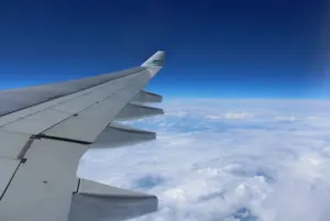 A wing and clouds seen from a plane window, the travel theme of the site
